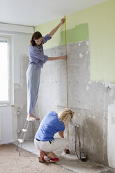 Young women measuring wall for renovation - FOLF00031