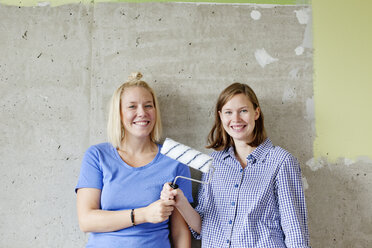 Young women standing by wall and holding paint roller - FOLF00037