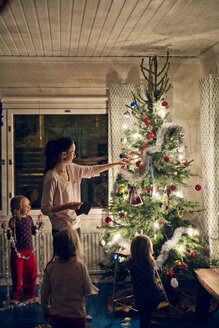 Mutter mit Töchtern beim Schmücken des Weihnachtsbaums - FOLF00056