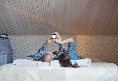 Couple lying on bed and using smart phone - FOLF00061