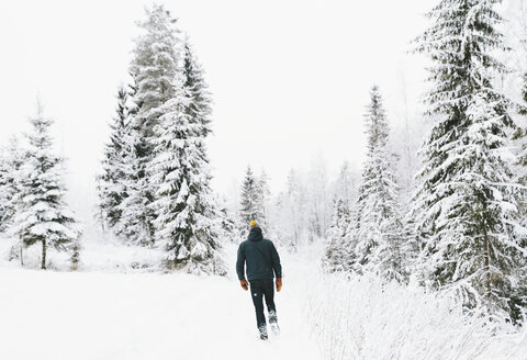 Rückansicht eines Mannes, der durch Schnee geht - FOLF00110