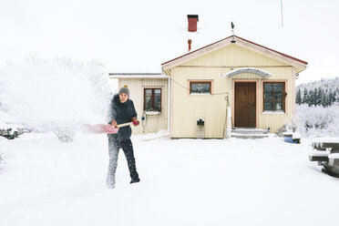 Mann beim Schneeschaufeln vor einem Haus - FOLF00112