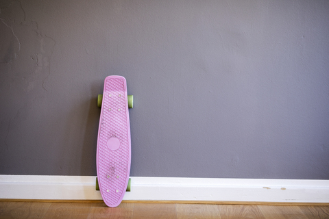 Rosa Skateboard an die Wand gelehnt, lizenzfreies Stockfoto