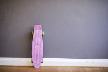 Pink skateboard leaning against wall - FMKF04972
