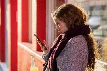 Teenager-Mädchen liest Textnachricht, hält Flasche mit Getränk - FMKF04977