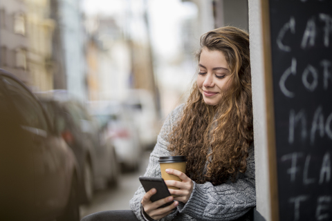 Teenage girl drinking coffee, reading text messages stock photo