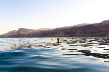 Woman swimming in sea against clear sky during sunset - CAVF28402
