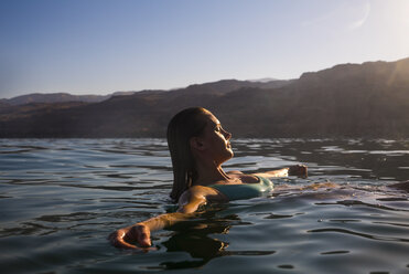 Frau schwimmt Meer gegen klaren Himmel bei Sonnenuntergang - CAVF28406