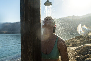 Woman taking shower while standing against sky - CAVF28407