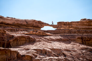 Woman walking on rock formation against clear sky - CAVF28408