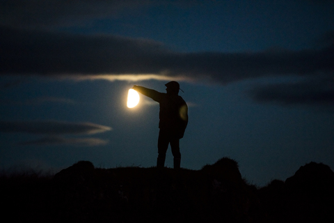 Optische Täuschung der Silhouette Mann berühren Sonne gegen bewölkten Himmel bei Sonnenuntergang, lizenzfreies Stockfoto