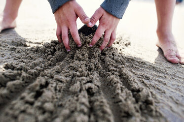 Ausgeschnittenes Bild eines Jungen, der am Strand mit Sand spielt - CAVF28496