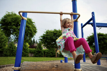 Fröhliches Mädchen hängt an einem Affengitter im Park - CAVF28499