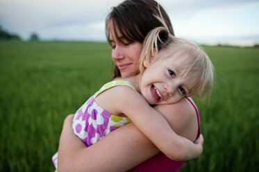Portrait of happy girl being carried by mother on grassy field against sky - CAVF28512