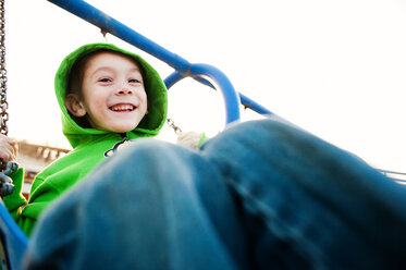 Low angle portrait of boy swinging against sky - CAVF28520