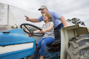 Farmer showing his daughter, how to drive a tractor - ZEF15226