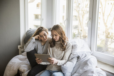 Zwei Mädchen im Teenageralter benutzen Tablet zu Hause - FMKF04993