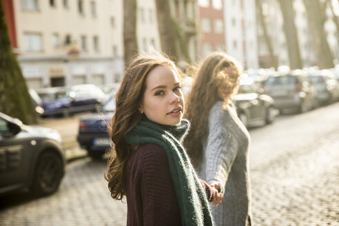 Porträt eines Teenagers, der Hand in Hand mit seiner besten Freundin auf der Straße geht - FMKF04999