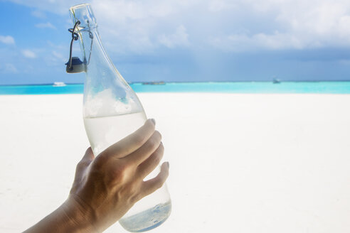 Malediven, eine Frau hält eine Flasche Wasser am Strand in der Hand - ZEF15244