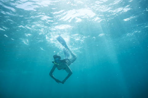 Woman with fins and snorkel diving under water stock photo