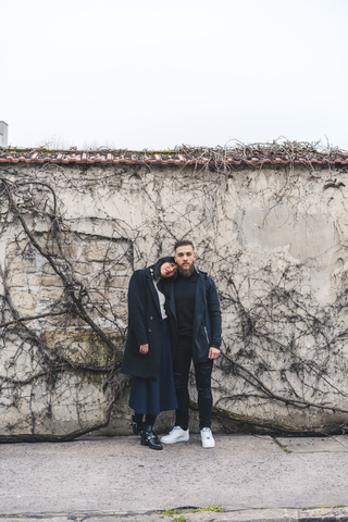Junges Paar vor einer Mauer stehend, lizenzfreies Stockfoto
