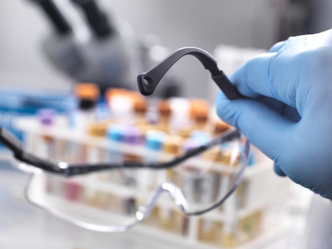 Medical technician holding protective glasses with human samples on the laboratory bench stock photo