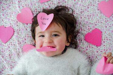 Porträt eines kleinen Mädchens mit rosa herzförmigen Post-it-Aufklebern - GEMF01905