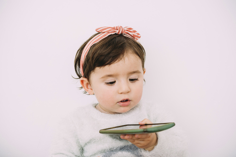 Portrait of baby girl looking at cell phone stock photo