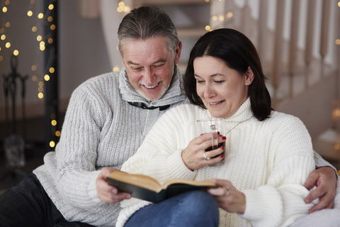 Happy mature couple reading a book in living room stock photo