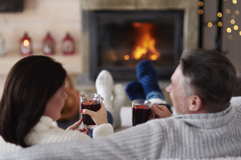 Mature couple with hot drinks in living room at the fireplace stock photo