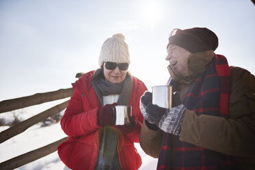 Happy mature couple with hot drinks outdoors in winter - ABIF00203