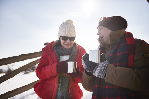 Glückliches reifes Paar mit heißen Getränken im Freien im Winter - ABIF00203