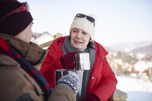 Älteres Paar mit heißen Getränken im Gespräch im Freien im Winter - ABIF00205