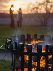 Kohlenbecken mit brennendem Holz, Silhouetten von Mann und Frau im Hintergrund - FOLF00339