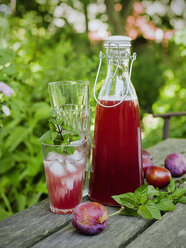 Pflaumensaft in Glas und Karaffe, Pflaumen und ein Stapel Gläser auf dem Tisch - FOLF00361