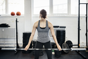 Junge Frau trainiert mit Langhantel im Fitnessstudio - FOLF00410