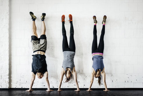 Young women and man practicing handstand in gym - FOLF00417