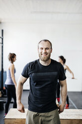 Junger Mann und Frauen stehen im Fitnessstudio - FOLF00431