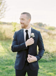 Portrait of groom standing and adjusting boutonniere - FOLF00464