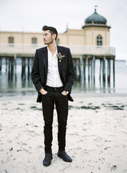 Young man wearing black suit on sandy beach - FOLF00571