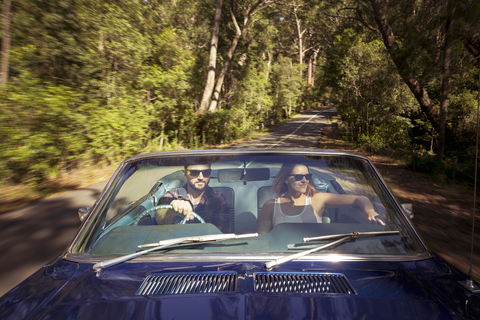 Paar fährt mit dem Auto durch den Wald, lizenzfreies Stockfoto