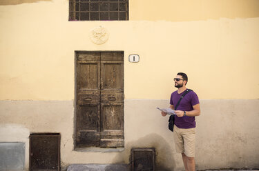 Tourist mit Landkarte vor einem alten Gebäude in Siena - FOLF00592