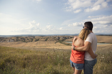 Hugging couple looking at field landscape - FOLF00593