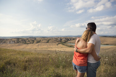 Umarmendes Paar mit Blick auf eine Feldlandschaft - FOLF00593