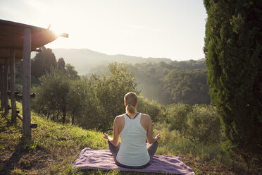 Woman in lotus position facing green hills - FOLF00603