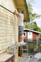 Erwachsener Mann beim Renovieren einer Hauswand - FOLF00746
