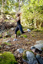 Mid adult woman running through forest - FOLF00784