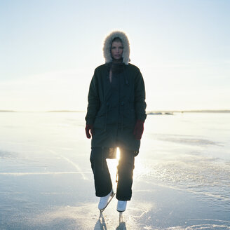 Mittlere erwachsene Frau in Schlittschuhen auf einem zugefrorenen See stehend - FOLF00801