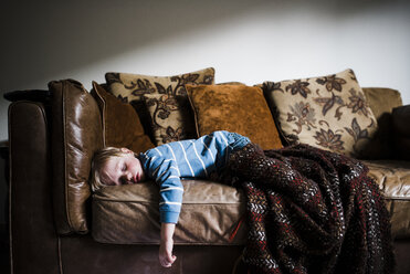 Junge schläft auf der Couch zu Hause an der Wand - CAVF28534