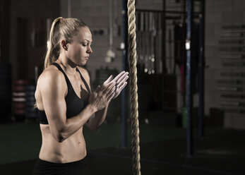 Seitenansicht einer Sportlerin, die sich vor dem Training im Fitnessstudio die Hände einkreidet - CAVF28551
